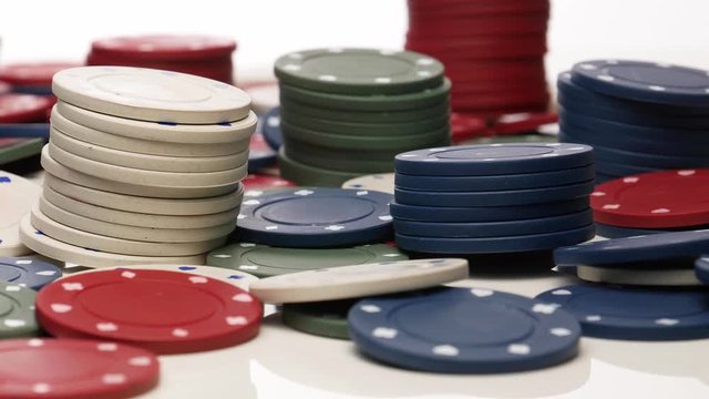Piles of green, white and red pocker chips  on a white background slowly rotating in circular mtion