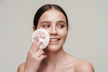 Image of pleased young shirtless woman using makeup pad and smiling