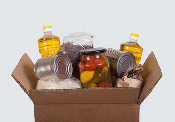 Box with a set of products from cereals, rice, vegetable oil, legumes and canned vegetables on a light background. Help, charity. Social. donation.