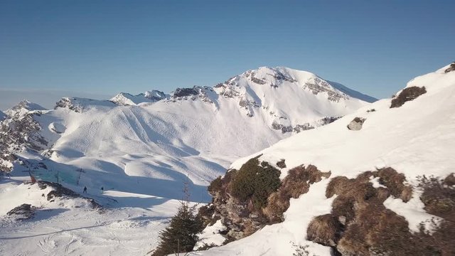 Aerial - Drone reveal shot of skiers at the skislope on the mountains of Portes Du Soleil in 4K