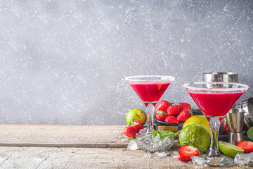 Summer cold alcohol drink. Strawberry margarita cocktail, with lime, mint and fresh strawberry on rustic wooden background