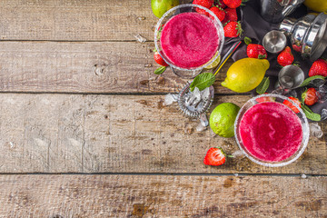 Summer cold alcohol drink. Strawberry margarita cocktail, with lime, mint and fresh strawberry on rustic wooden background