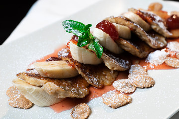 Juicy fritters with fruit for breakfast. Tasty cheesecakes with jam and bananas. Beautiful food from the restaurant cooked by a chef cook. Sweet dessert. A dish of flour and eggs.