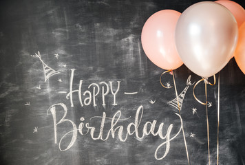 The inscription white on the chalk board of a HAPPY BIRTHDAY next to pink balloons. Congratulation,...