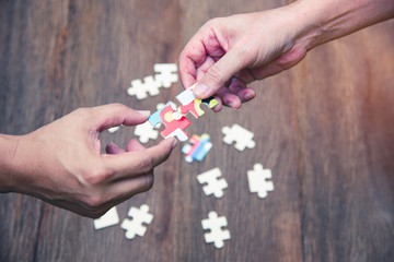 Two hands joint puzzle jigsaw for successful negotiation, Teamwork support building team cooperation. Connect business communication to solve the problem together by  creative the strategy solution.