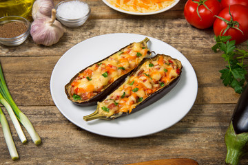 Eggplant stuffed with meat and vegetables and baked with cheese on a rustic wooden table. Selected focus.