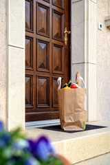 Contactless food delivery service concept. Paper bag with groceries delivered and left outside at...