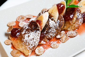 Juicy fritters with fruit for breakfast. Tasty cheesecakes with jam and bananas. Beautiful food from the restaurant cooked by a chef cook. Sweet dessert. A dish of flour and eggs.