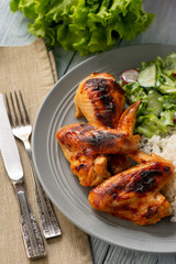 Grilled chicken wings and drumsticks, served with boiled rice and salad.