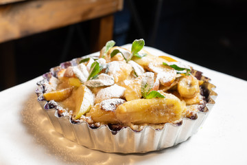 Juicy banana pie. Delicious Thanksgiving apple pie with mint or basil. Baking in the oven. Pie with banana. Sweet cupcake with baked fruit sprinkled with powder.
