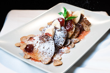 Juicy fritters with fruit for breakfast. Tasty cheesecakes with jam and bananas. Beautiful food from the restaurant cooked by a chef cook. Sweet dessert. A dish of flour and eggs.