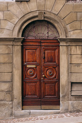 Fototapeta na wymiar Brown wooden old door in the centre of Bergamo, Italy. Toned photo. 