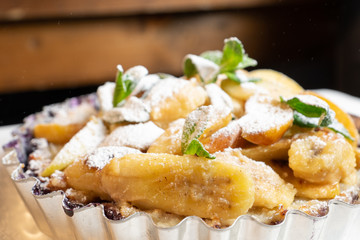 Juicy banana pie. Delicious Thanksgiving apple pie with mint or basil. Baking in the oven. Pie with banana. Sweet cupcake with baked fruit sprinkled with powder.