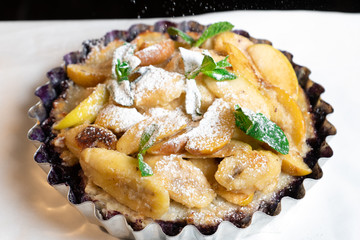 Juicy banana pie. Delicious Thanksgiving apple pie with mint or basil. Baking in the oven. Pie with banana. Sweet cupcake with baked fruit sprinkled with powder.