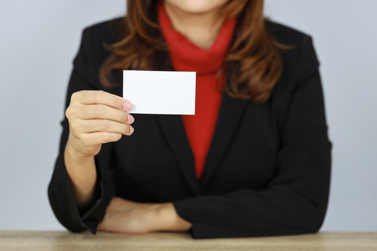 Business woman in black business suit uniform holding and showing name card on white background studio (advertisement concept)