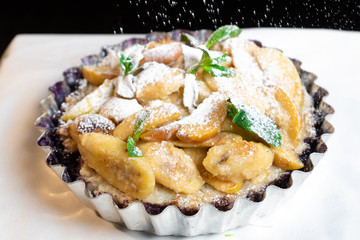 Juicy banana pie. Delicious Thanksgiving apple pie with mint or basil. Baking in the oven. Pie with banana. Sweet cupcake with baked fruit sprinkled with powder.