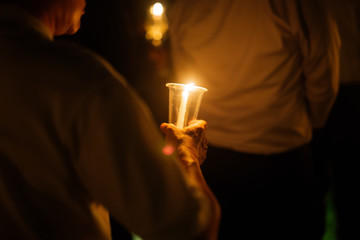 A prayer man holding a lighted candle in his hand for pray