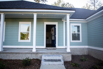 Front view of a brand new construction house with blue siding, a ranch style home with a yard
