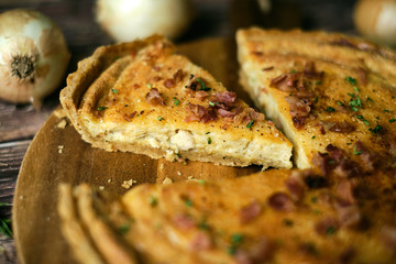Homemade cheesy quiche lorraine for brunch. set on wooden cafe table background.