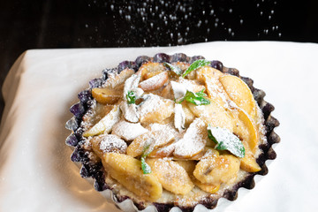 Juicy banana pie. Delicious Thanksgiving apple pie with mint or basil. Baking in the oven. Pie with banana. Sweet cupcake with baked fruit sprinkled with powder.