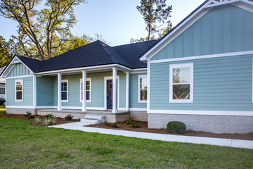 Front view of a brand new construction house with blue siding, a ranch style home with a yard