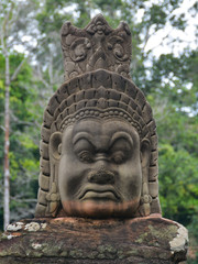 Fototapeta na wymiar Face of a demon sculpture (asura) in the pathway to Bayon Temple. Angkor Temples in Siem Reap, Cambodia
