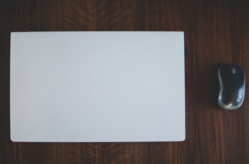 modern style white laptop with mouse on a dark wooden table
