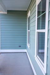 Front view of the small porch of a brand new construction house with blue siding, a ranch style home with a yard