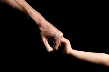Father and son fist bump on black background with outstretched arms