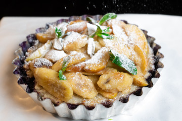 Juicy banana pie. Delicious Thanksgiving apple pie with mint or basil. Baking in the oven. Pie with banana. Sweet cupcake with baked fruit sprinkled with powder.