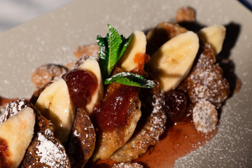 Juicy fritters with fruit for breakfast. Tasty cheesecakes with jam and bananas. Beautiful food from the restaurant cooked by a chef cook. Sweet dessert. A dish of flour and eggs.