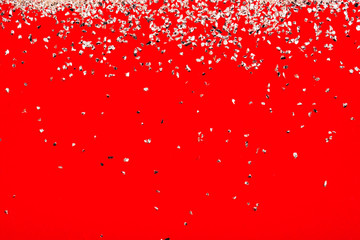 Red background with falling silver sparkles. Flat lay style