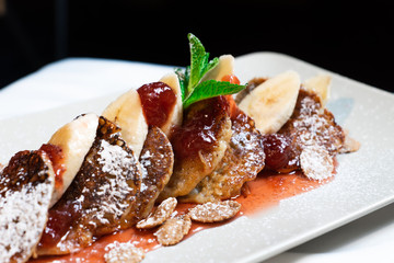 Juicy fritters with fruit for breakfast. Tasty cheesecakes with jam and bananas. Beautiful food from the restaurant cooked by a chef cook. Sweet dessert. A dish of flour and eggs.