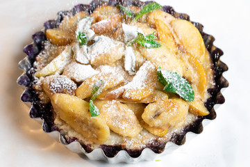 Juicy banana pie. Delicious Thanksgiving apple pie with mint or basil. Baking in the oven. Pie with banana. Sweet cupcake with baked fruit sprinkled with powder.