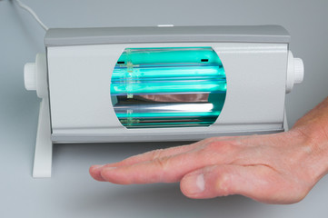 Hand of patient under ultraviolet lamp close up