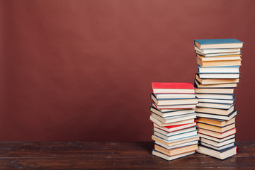 a lot of stacks of educational books to study at the college library on a brown background