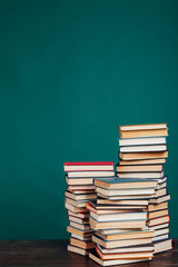 lots of stacks of educational books to teach in the school library on a green background