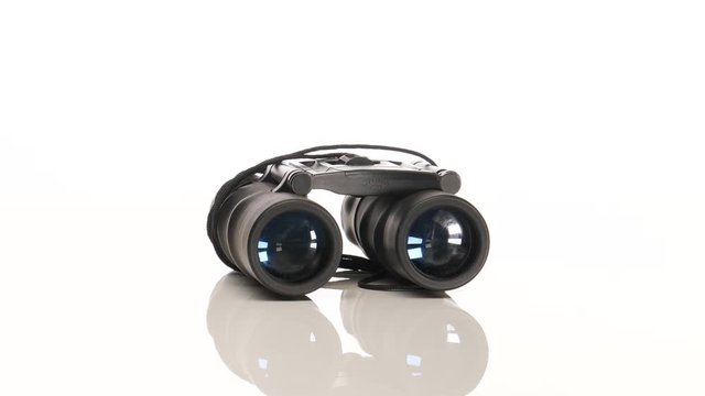 A pair of black binoculars rotating in circular motion on a white background