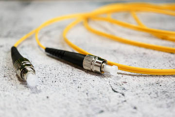 yellow fiber optic cable with black connectors on grey background close up