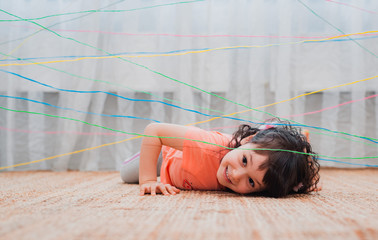 little girl child climbs through a rope web, a game obstacle quest indoors.