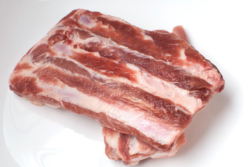 Raw pork ribs on a white plate. Pork tenderloin. Fresh meat.