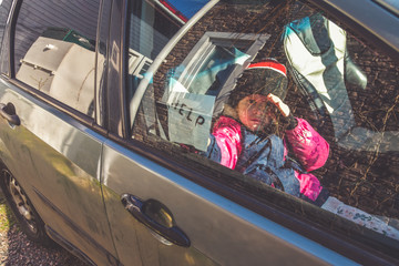 child in the car holds a note with the word help