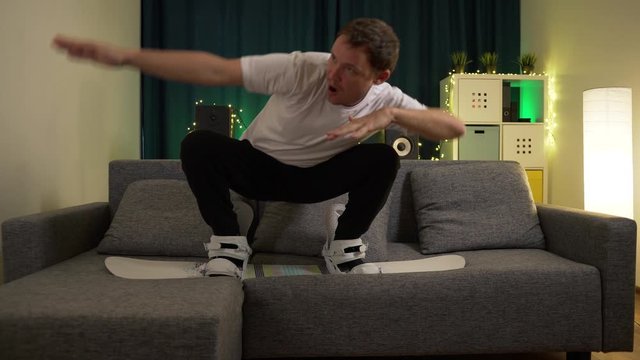 a man jumps on a snowboard on the couch