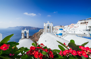 Fototapeta premium bell towers of Greek Orthodox Church (Agios Spiridonas and Anastasi) and panorama of Oia with Aegean sea, Santorini island, Cyclades, Greece