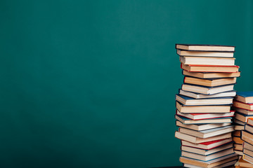 lots of stacks of educational books to teach in the school library on a green background