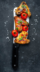 grilled chicken wings with spices on a knife on a stone background with copy space for your text