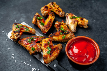 grilled chicken wings with spices on a knife on a stone background 