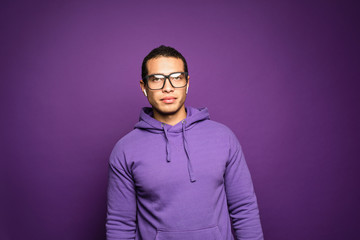 Smart intelligent young handsome man wearing eyeglasses standing isolated over purple background.