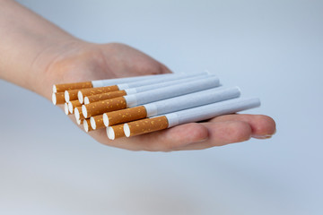 The girl holds a lot of loose cigarettes in her hands. White background