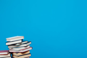 lots of stacks of educational books to teach in the school library on a blue background